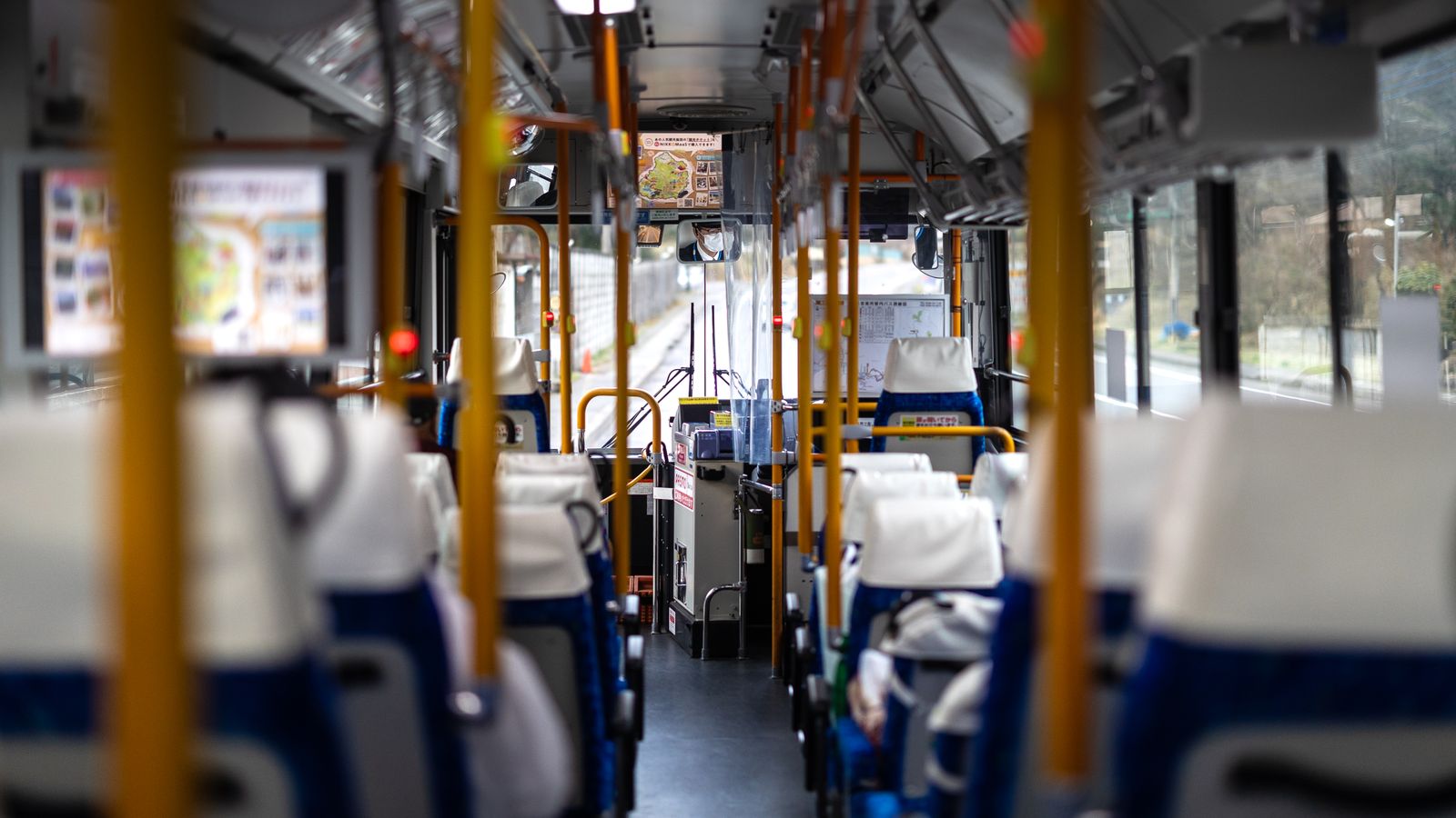 青い座席と黄色の手すりが並ぶ路線バスの車内