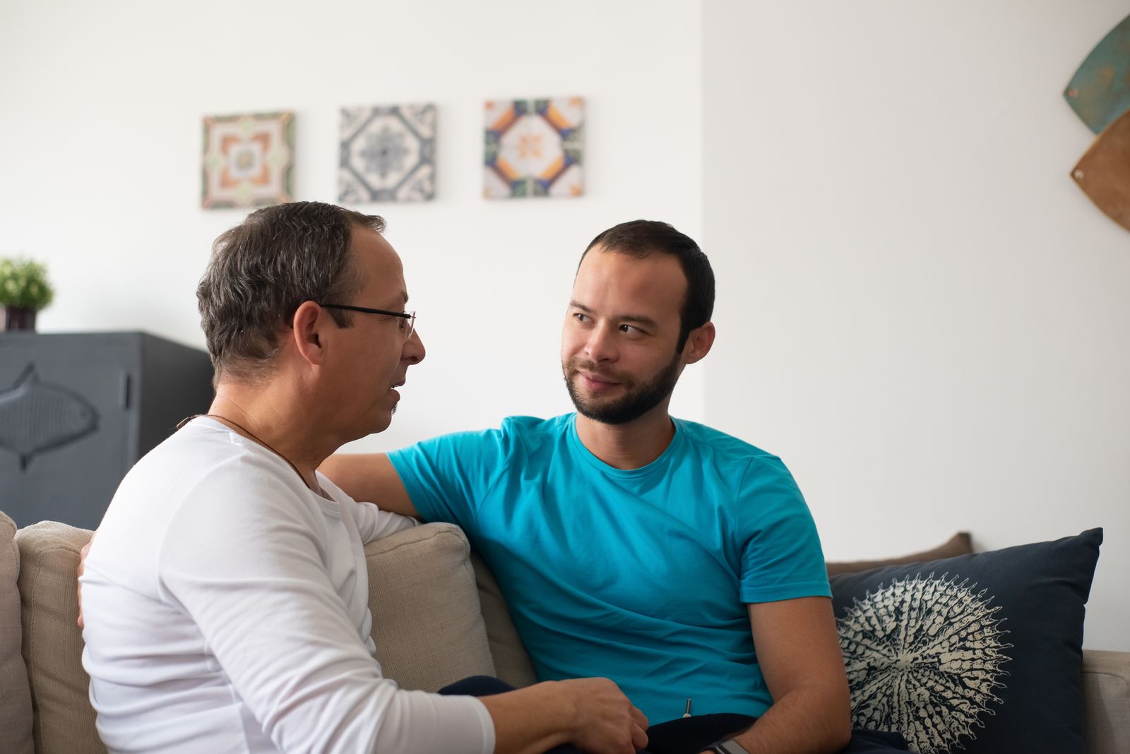 リビングのソファに座り、向かい合って話をするシニアの男性と若い男性