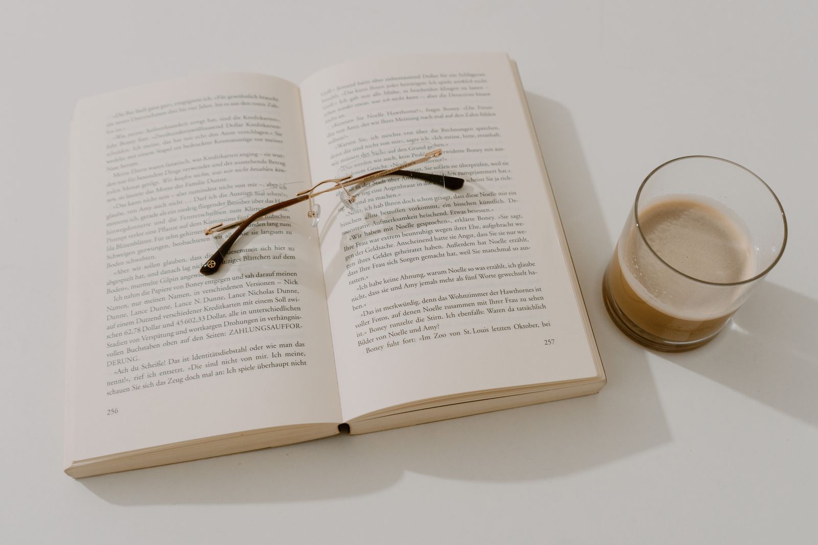 開いた本の上に置かれた老眼鏡と、そばに置かれたコーヒー